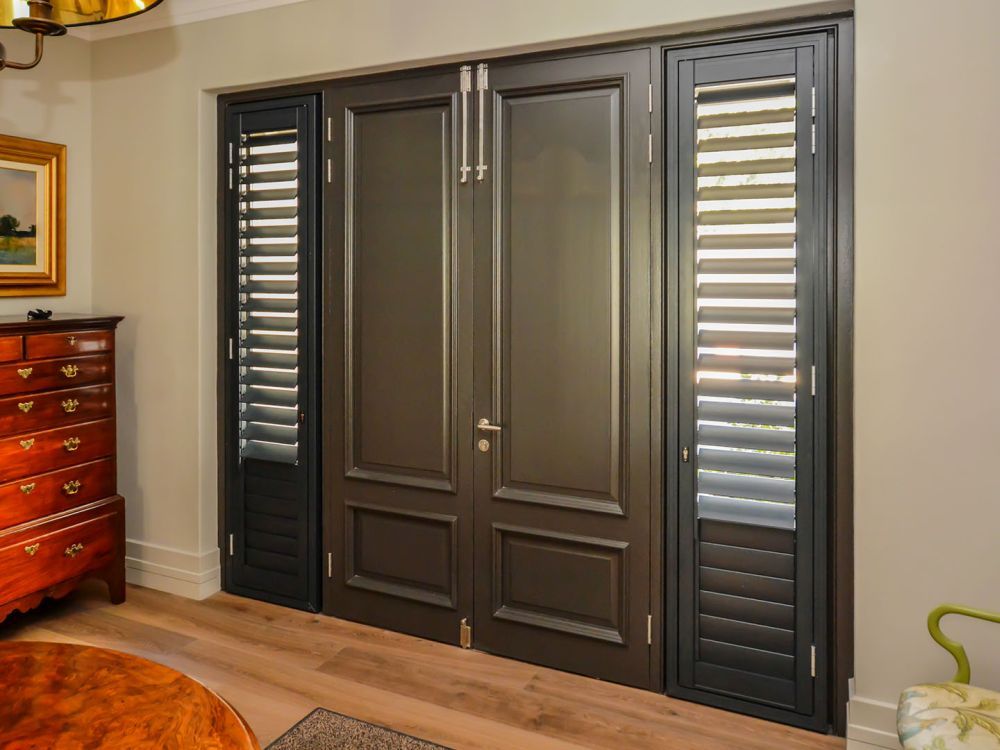 A double door with side-light windows covered with security shutters